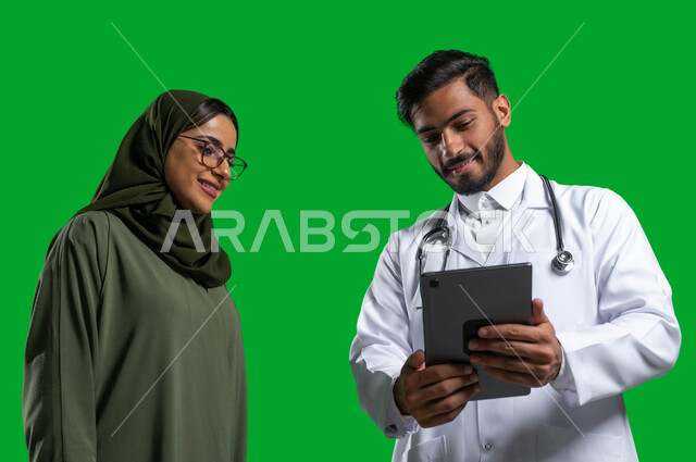 شرح و توضيح طريقة العلاج عبر جهاز التابلت, وصف الحالة المرضية و تقديم الاستشارات الطبية، بورتريه مقرب لطبيب عربي خليجي سعودي يرتدي المعطف و السماعة الطبية يتحدث مع المريضة, مفهوم الطب المنزلي, إعطاء العلاج المناسب للمرضى, كروما، خلفية خضراء. 