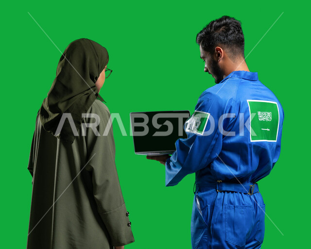 احتراف قيادة وصيانة السفن الفضائية, توجيه عملية سير المركبات الفضائية عبر الحاسوب والاقمار الصناعية, مفهوم الملاحة الجوية و هندسة الفضاء, بورتريه من الخلف لرائد فضاء عربي خليجي سعودي يرتدي بدلة الفضاء السعودية يقف مع إمرأة سعوديه محجبه, كروما, خلفية خضراء