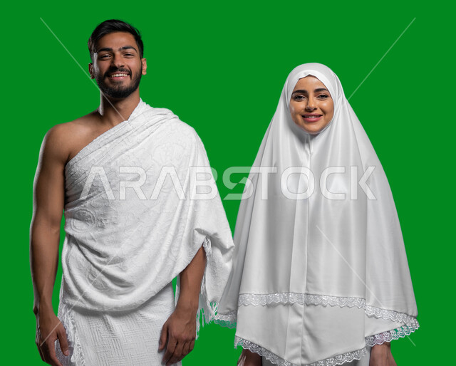 مفهوم الألفة بين الزوجين, المحافظة على الصلوات الخمس, الإكثار من العبادات في الشهر المبارك, تلبية نداء الله الى الحج و العمرة، بورتريه لرجل إمرأة  عربيان خليحيان سعوديان مبتسمان يرتديان ثياب الإحرام يستعدان لأداء العمرة في شهر رمضان، كروما, خلفية خضراء.