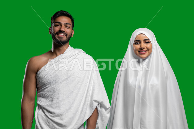فضل أداء العمرة في شهر رمضان المبارك, تلبية نداء الله الى الحج و العمرة، المحافظة على الصلوت الخمس, بورتريه مقرب لزوجان عربيان خليحيان سعوديان مبتسمان يرتديان ثياب الإحرام يستعدان لزيارة بيت الله الحرام، كروما, خلفية خضراء.