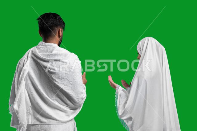 رفع اليدين للأعلى والدعاء والتضرع إلى الله, فضل اداء العمرة في شهر رمضان المبارك, تلبية نداء الله الى الحج و العمرة،  بورتريه مقرب من الخلف  لزوجان عربيان خليحيان سعوديان يرتديان ثياب الإحرام، المحافظة على الصلوات الخمس, اسلاميات وعبادة، كروما, خلفية خضرا