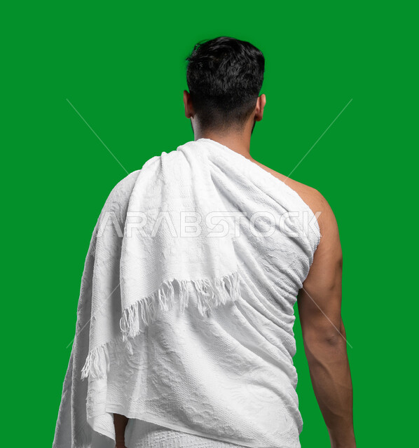 المحافظة على الصلوات الخمس, فضل العمرة في شهر رمضان المبارك, التقرب الى الله بالأعمال الصالحة,  بورتريه من الخلف لشاب عربي سعودي خليجي يرتدي ملابس الإحرام يستعد لتلبية نداء الله الى الحج  و العمرة، كروما، خلفية خضراء.