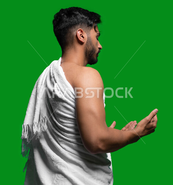 التوسل إلى الله وطلب المغفرة, تلبية نداء الله الى الحج و العمرة, المحافظة على الصلوات الخمس, بورتريه جانبي لشاب عربي سعودي خليجي يرتدي ملابس الإحرام يرفع يديه ويدعو الله بإيماءات وجه تدل على التوسل و التضرع، كروما، خلفية خضراء.