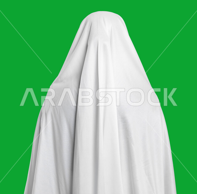 لباس الحشمة و الستر للمرأة المسمله, التقرب إلى الله بالأعمال الصالحة، المحافظة على الصلوات الخمس, فضل العمرة في شهر رمضان المبارك، بورتريه مقرب من الخلف لامرأة عربية سعودية خليجية ترتدي ملابس الصلاة البيضاء, اداء مناسك الحج والعمرة، كروما، خلفية خضراء.