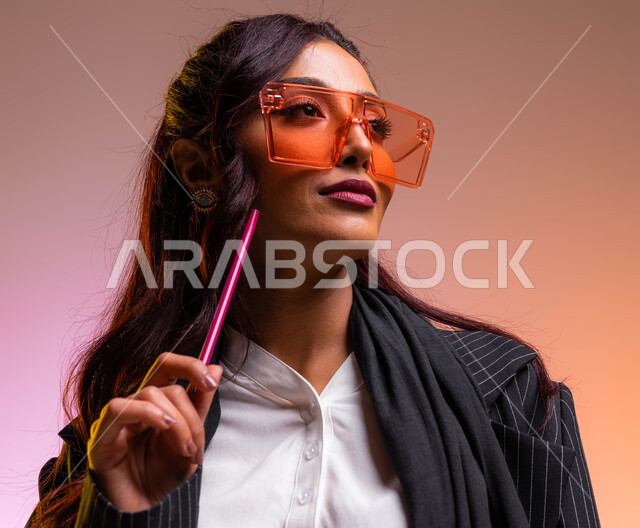 سيدة أعمال أنيقة ترتدي نظارات شمسية ملونة عصرية، مهن وأعمال نسائية سعوديه، بورتريه مقرب لمعلمة عربية خليجية سعودية ترتدي اللباس الرسمي تمسك بيدها قلم تقوم بالنظر إلى شيء ما, الاهتمام والاعتناء بالمظهر الخارجي والاناقه، خلفية ملونة