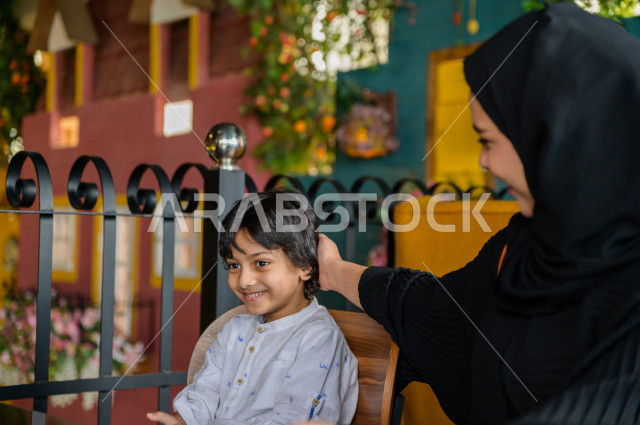 طفل عربي خليجي سعودي يقضي وقته مع والدته في المطعم بايماءات و تعابير وجه تدل على السعادة ، قضاء العطلة مع العائلة ، أجواء عائلية ترفيهية ، جلسات فريدة و مميزة ، مطاعم و كافيهات في السعودية