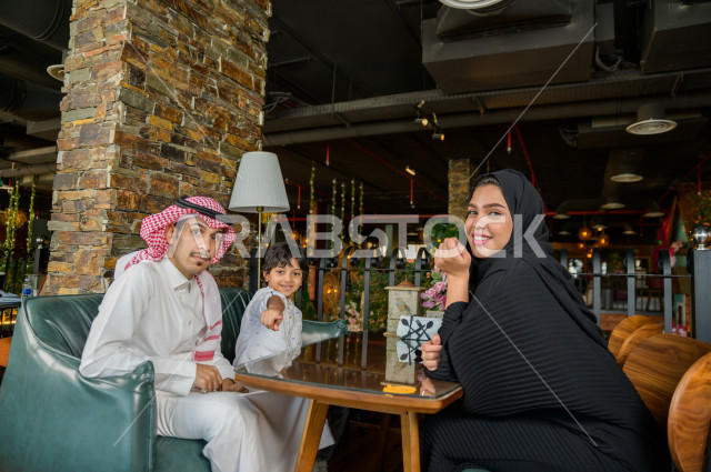 عائلة عربية خليجية سعودية تقضى وقتا ممتعا على مائدة الطعام في المطعم ، قضاء أوقات عائلية ترفيهية ، قضاء العطلة مع العائلة ، جلسات فريدة و مميزة ، مطاعم و كافيهات في السعودية