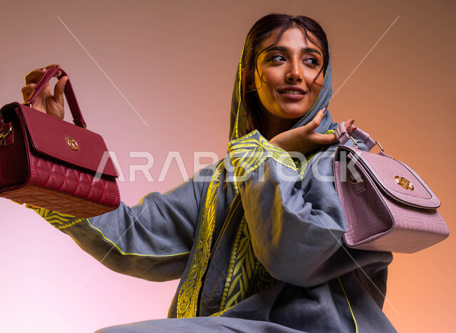 The joy of shopping and buying new bags and different models, gestures of admiration and happiness for owning an elegant bag, a close-up portrait of a Saudi Arabian Gulf woman wearing the modern abaya, Saudi women's products and international luxury brand