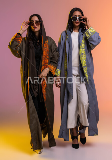 ايماءات الثقة والوقوف أمام الكاميرة، الاحتراف في عرض آخر صيحات الموضة، بورتريه لعارضتان عربيتان سعوديتان خليجيتان، ارتداء العباءة الخليجية والنظارات الشمسية، صورة الجسم بالطول الكامل، منتجات نسائيه سعوديه، شراء الأزياء والاكسسوارات, خلفية ملونة
