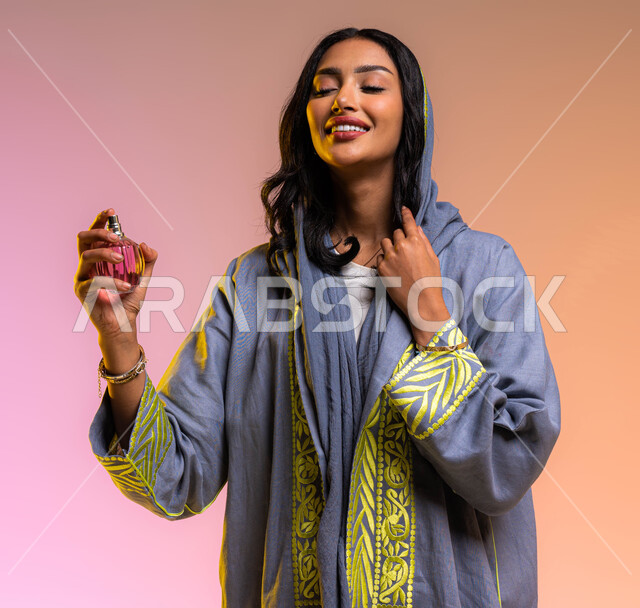 The concept of elegance and interest in the external appearance, perfuming and perfuming with oud and essential oils, marketing perfume products and women's lotions, a portrait of a Saudi Arabian Gulf woman wearing an abaya and spraying perfume, a colored