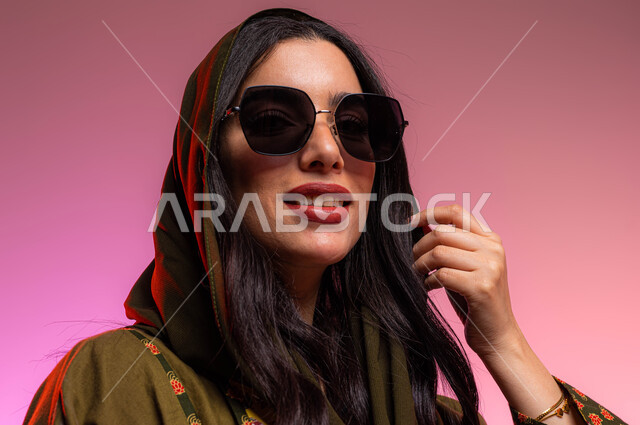 ارتداء النظارات الشمسية, بورتريه مقرب لعارضة أزياء عربية سعوديه خليجية ترتدي عباءه أنيقة, تسوق وشراء أحدث المنتجات, متابعة الموضة والجمال والاناقة، ملابس واكسسوارات نسائية بتصاميم عصرية, خلفية ملونة