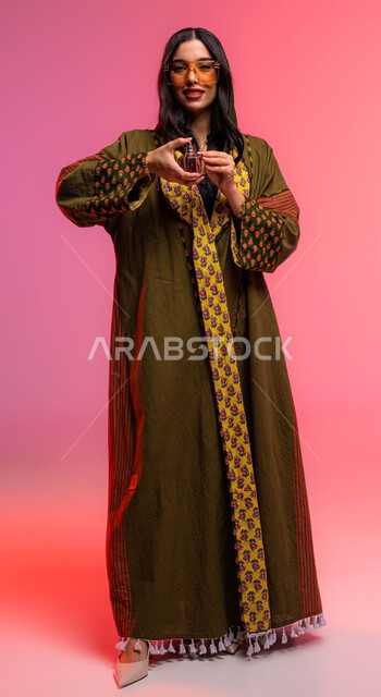 The concept of elegance and concern for the external appearance, a portrait of a Saudi Arabian Gulf woman spraying perfume, marketing perfume products and women's lotions, perfuming and perfuming with oud and essential oils, wearing an abaya and sunglasse