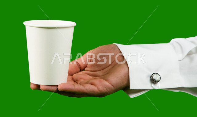Delivery of purchases and orders to customers, buying fresh coffee from Saudi cafes, LED portrait of a Saudi Arabian Gulf man holding a cup of coffee, mock-up of a cardboard cup, fast and safe delivery services for hot drinks, green background chroma