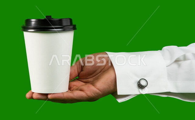 Fast and safe delivery services for hot drinks, cardboard cup mock-up, buying fresh coffee from Saudi cafes, LED portrait of a Saudi Arab Gulf man carrying a cup of coffee, delivery of purchases and orders to customers, green background chroma