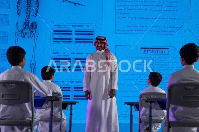 طرق التعليم المتطورة، معلم عربي خليجي سعودي يقوم بشرح الدروس للطلاب، أساليب وإستراتيجيات جديدة في نظام  التعليم في المدارس السعودية، التعليم المتطور باستخدام شاشات إلكترونية وتقنيات حديثة، رؤية مستقبلية 2030