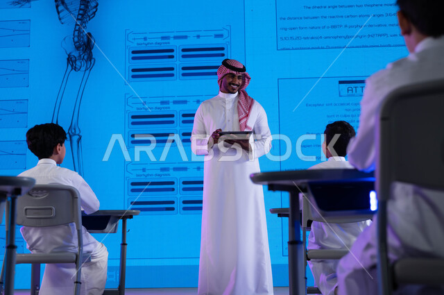 التنوع في استراتيجيات التعليم في المدارس السعودية، التعليم المتطور باستخدام شاشات إلكترونية وتقنيات حديثة، معلم عربي خليجي سعودي يستخدم جهاز التابليت في الشرح والتوضيح، أساليب وإستراتيجيات جديدة في نظام  التعليم في المدارس السعودية، رؤية مستقبلية 2030