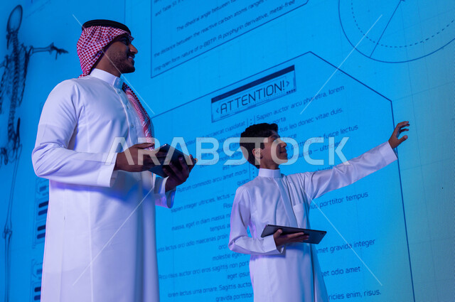 Advanced education using electronic screens and modern technologies, a Saudi Gulf Arab student and teacher using the tablet in explanation and clarification, new methods and strategies in the education system in Saudi schools, future vision 2030