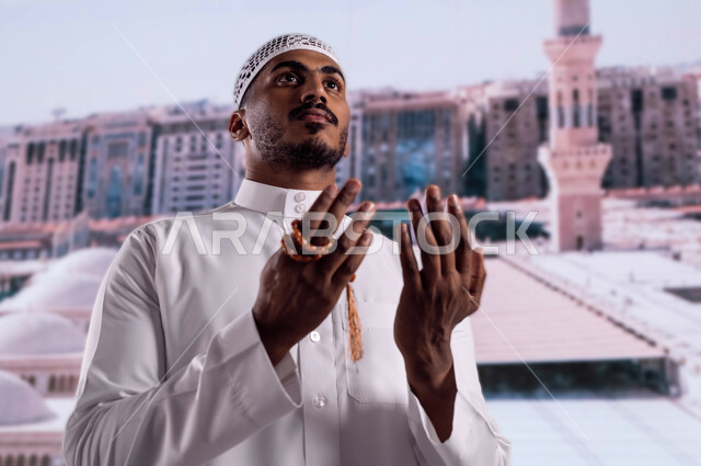 العمارة العريقة الإسلامية لقباب المساجد في المدينة المنورة، ثواب الصلاة والدعاء في مسجد رسول الله، صورة مقربة لرجل عربي سعودي خليجي يمسك بيده سبحة ويرتدي الزي السعودي التقليدي ويقف أمام المسجد النبوي الشريف ويدعو الله تعالى، خلفية القبب لمسجد نبي الله