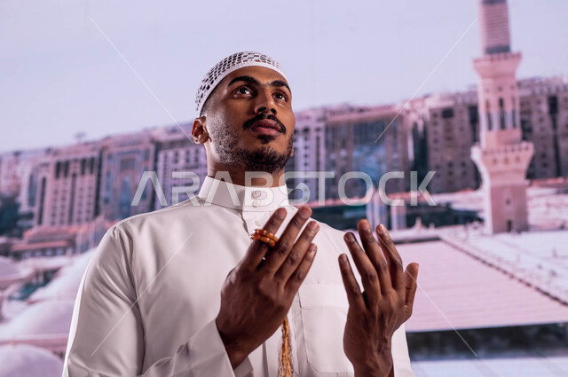 فضل الصلاة والدعاء في مسجد رسول الله، صورة مقربة  لرجل عربي سعودي خليجي يرتدي الزي السعودي التقليدي يقف أمام المسجد النبوي الشريف ويدعو الله تعالى، العمارة الإسلامية العريقة لقباب المساجد في المدينة المنورة، خلفية القبب لمسجد النبي محمد صلى الله عليه وسلم