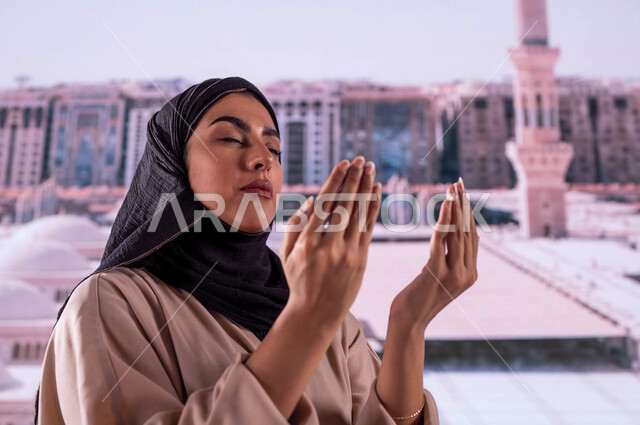 العمارة الإسلامية العريقة لبناء المساجد في المدينة المنورة, فضل وثواب الصلاة والدعاء في مسجد رسول الله, صورة مقربة لإمرأة عربية سعودية خليجية ترتدي عباءة ملونة تقف أمام المسجد النبوي الشريف وتدعو الله تعالى, خلفية القبب لمسجد النبي محمد صلى الله عليه وسلم