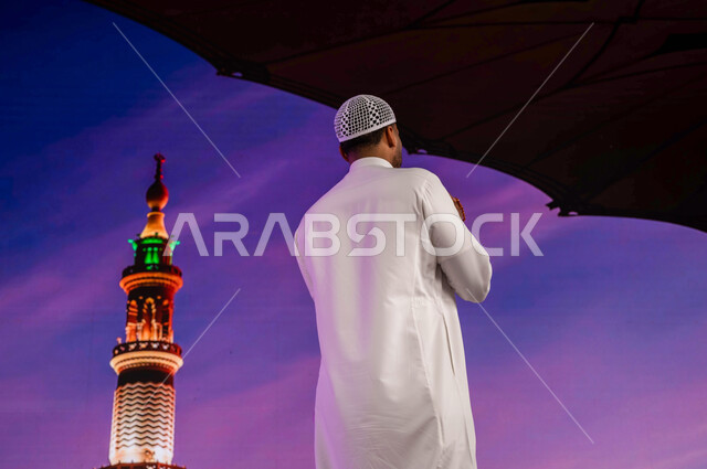 خلفية المئذنة و المظلات الإلكترونيه في مسجد رسول الله، أماكن و معالم إسلامية مقدسه في السعوديه، صورة من الخلف لشاب مسلم عربي سعودي خليجي في ساحة المسجد النبوي الشريف في المدينة المنورة، الصلاة و الدعاء و العبادة وذكر الله تعالى