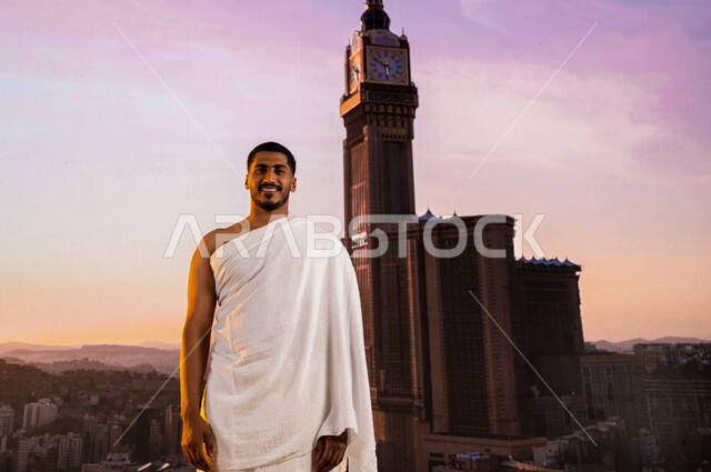 فضل و ثواب العمره في شهر رمضان المبارك، خلفية أبراج الحرم المكي و برج الساعة، شاب مسلم عربي سعودي خليجي مبتسم يرتدي ملابس الإحرام، قدوم حجاج الداخل الى مكة المكرمة لأداء فريضة الحج في شهر ذو الحجه، موسم الحج 2023