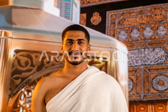 ايماءات السعادة والفرح، الحرم المكي الشريف في مكة المكرمة بالمملكة العربية السعودية، العبادة والتقرب إلى الله، حاج عربي سعودي خليجي يرتدي ملابس الإحرام ينظر الى الكاميرا، أداء مناسك الحج والعمرة، خلفية الكعبه المشرفة ومقام إبراهيم عليه السلام