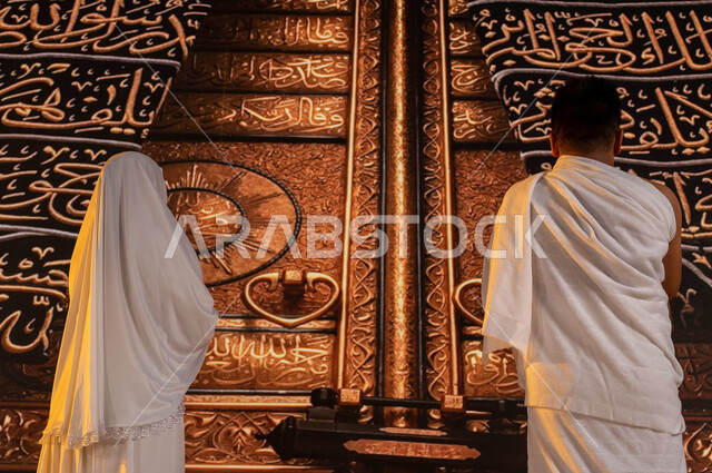 أدعية وأذكار اسلامية، صورة مقربة من الخلف لحاجان عربيان سعوديان  خليجيان يقفان أمام الباب الذهبي للكعبة المشرفة في المسجد الحرام, الدعاء وطلب المغفرة, أداء العمرة في رمضان, الطواف حول بيت الله الحرام في مكة المكرمة, مناسك الحج في ذو الحجة 2023