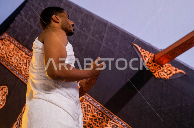 فضل العمرة في شهر رمضان المبارك, أداء فريضة الحج في ذي الحجة, صورة من الجانب لحاج عربي سعودي خليجي يرتدي زي الإحرام, الطواف حول الكعبة, الدعاء والتوسل إلى الله في المسجد الحرام, صورة مقربة لميزاب الكعبة المشرفة