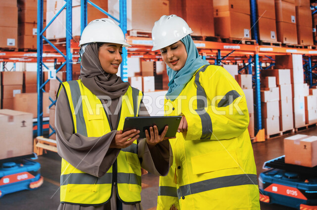 Integration of technology and technology with work, use of tablets to ensure the presence and availability of goods, the processes of arranging and organizing local warehouses, a close-up of Saudi Gulf Arab women receiving officials in the warehouse depar