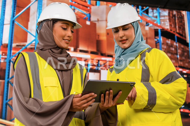 Integration of technology and technology with work, use of tablets to ensure the presence and availability of goods, the processes of arranging and organizing local warehouses, a close-up of Saudi Gulf Arab women receiving officials in the warehouse depar