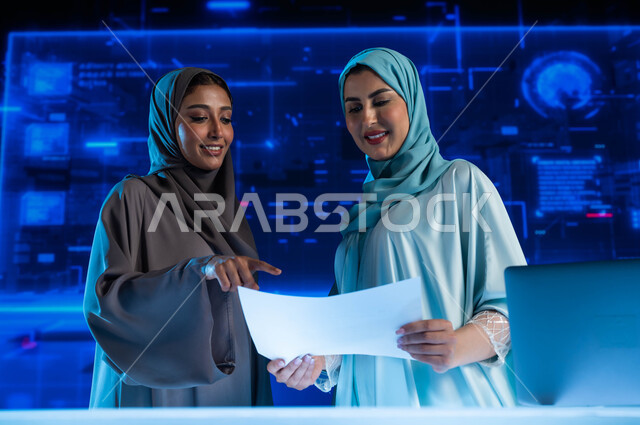  حوارات ونقاشات عمل، تطوير الشركات والمشاريع الاقتصادية، الاستثمار المالي والتجارة الالكترونية, موظفتان عربيتان خليجيتان سعوديتان في اجتماع عمل في مقر الشركة, مراقبة البورصة وسوق الأسهم، خلفية هولوجرامية ثلاثية الأبعاد.