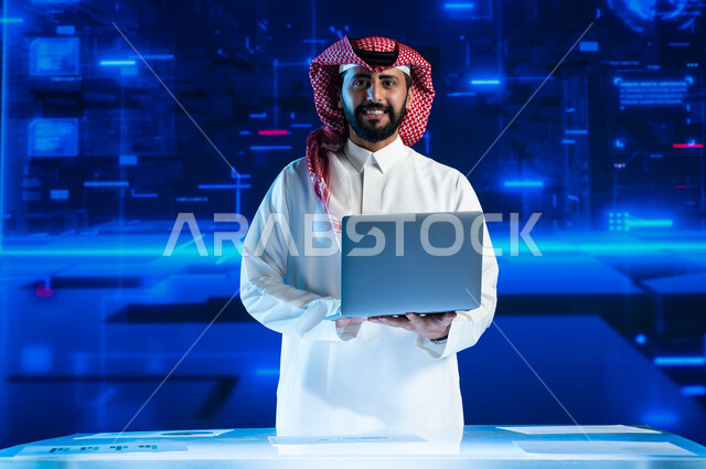 الاستثمار المالي والتجارة الالكترونية، تطوير الشركات والمشاريع الاقتصادية، سيد أعمال عربي خليجي سعودي مبتسم يرتدي الثوب السعودي التقليدي في مقر عمله بالشركة يحمل جهاز الحاسوب  ينظر إلى الكاميرا، خلفية شاشات هولوجرامية ثلاثية الأبعاد.
