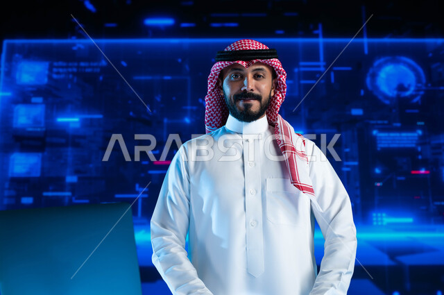 Development of companies and economic projects, financial investment and electronic commerce, a smiling Saudi Arabian Gulf businessman wearing the traditional Saudi dress at his workplace in the company looking at the camera, against the background of 3D 