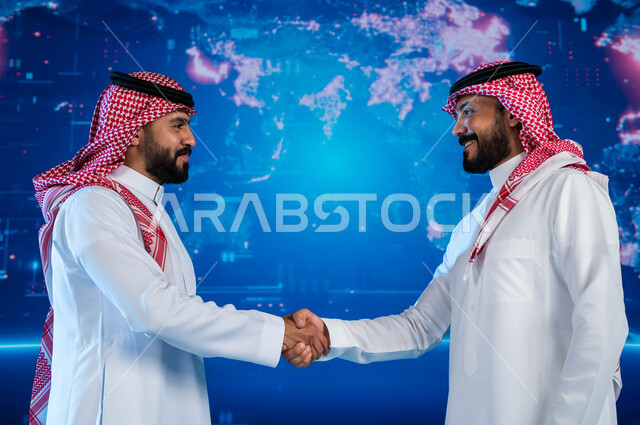 مشاركة الأفكار وتبادل الخبرات، التعاون بين المواطنين لتحقيق المصالح المشتركة, رجلا أعمال عربيان خليجيان سعوديان يرتديان الزي التقليدي يقومان بالمصافحة، التواصل الفعال بين المملكة العربية السعودية ودول العالم، خلفية شاشة هولوجرامية ثلاثية الابعاد.