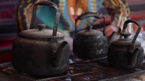 لقطة مقربة لأباريق الشاي العربية التقليدية وهي تغلي على النار مع ظهور شخص