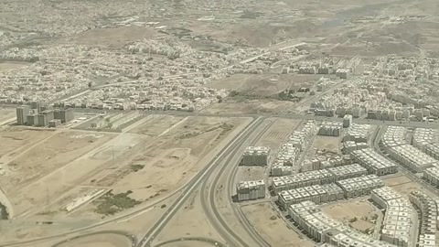 منظر جوي لمنطقة سكنية محاطة بالمناظر الطبيعية القاحلة والتلال.