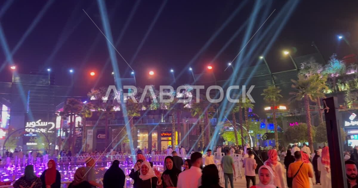 Green palm trees and luminous water nozzles, visitors gather in Square