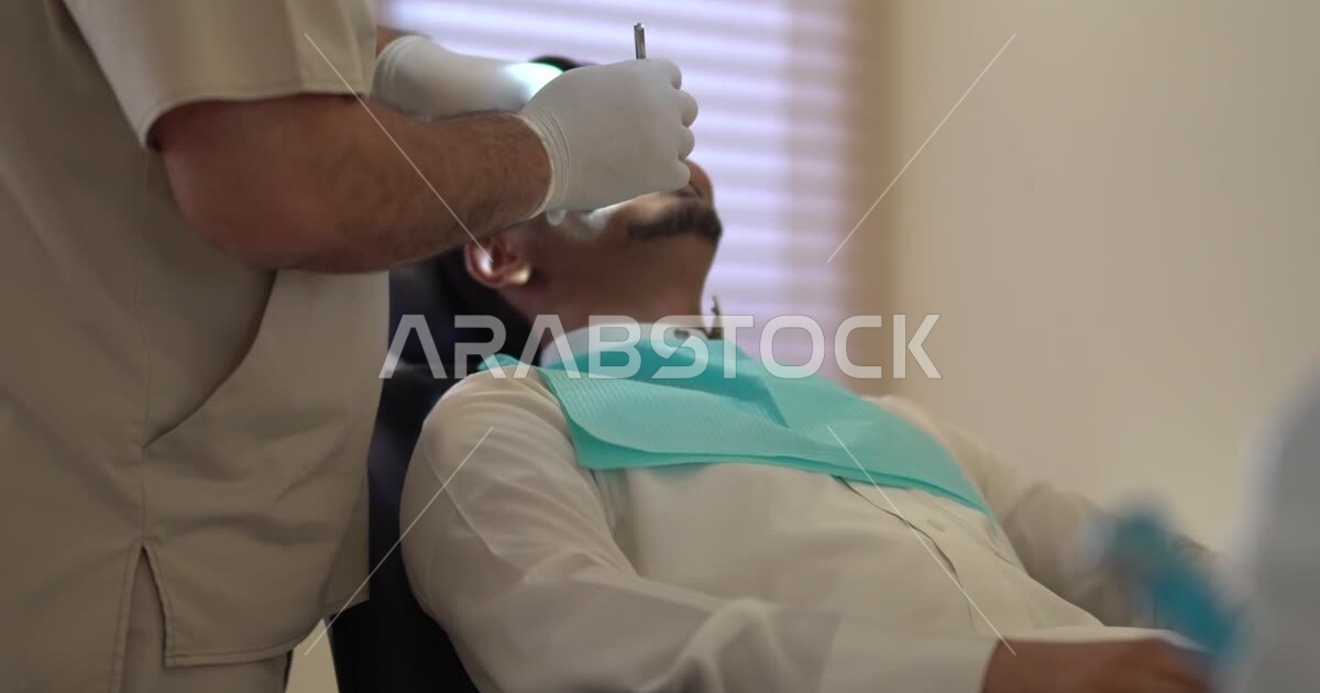 A Saudi Arabian Gulf dentist wearing medical gloves, examining and