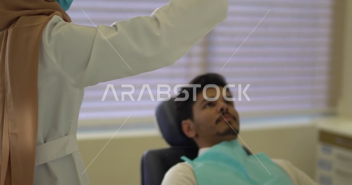 A Saudi Arabian Gulf dentist wearing medical gloves, examining and