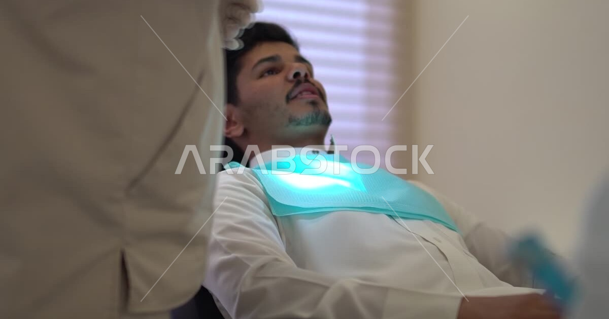 A Saudi Arabian Gulf dentist wearing medical gloves, examining and