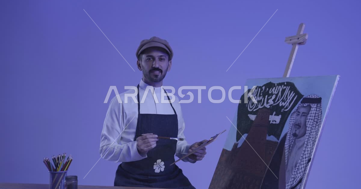 رسام عربي خليجي سعودي يرتدي مريلة الرسم يقوم بالرسم واستذكار اليوم ...