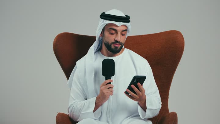 تقديم الأفكار ومناقشتها، تبادل الحوارات والتواصل الفعال، بورتريه لرجل عربي خليجي اماراتي يرتدي الكندوره والغتره البيضاء يحمل بيده مكبر الصوت يقوم بإلقاء الخطابات من الهاتف، إجراء المقابلات وطرح الأسئلة، خلفية رمادية