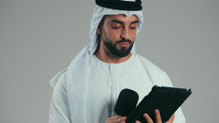 قراءة الملاحظات والمعلومات، بورتريه لرجل عربي خليجي اماراتى يرتدي الكندوره والغتره يحمل بيده الجهاز اللوحى ومكبر الصوت يقوم بإلقاء الخطابات، القيام بالحوارات والنقاشات، إعداد وتحضير أفكار الخطاب بشكل مسبق، خلفية رمادية