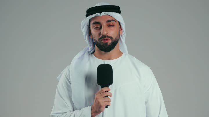 إلقاء المحاضرات وإقامة الندوات، تبادل الحوار والنقاش والتواصل الفعال، تقديم ورش العمل والدورات التدريبية، فن التحدث والخطابة، بورتريه لشاب عربي خليجي اماراتي يرتدي الكندورة والغترة يقف بثقه يمسك مكبر الصوت، خلفيه رماديه