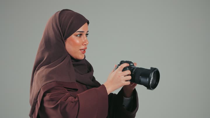 توثيق اللحظات وتخليدها في الذاكرة، سيده سعوديه تمسك كاميرا عالية الدقة وتلتقط الصور التذكارية، بورتريه من الجانب لإمرأة عربية خليجية اماراتيه محجبة ترتدي العباءة وتقوم بالتقاط الصور الفوتوغرافية، استكشاف العالم من خلال العدسة، تقنيات التصوير المبتكرة