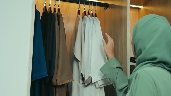 مفهوم الموضه والاناقه ، شراء المستلزمات النسائيه من المتجر ،الاستفاده بالعروض والخصومات ،تصوير مقرب لامرأة عربية خليجية إماراتية ترتدي عباءة أنيقة تقوم باختيار ملابس وعبايات من تشكيلة حديثة، سيده سعوديه تقوم بتجربة تسوق ضمن أجواء مريحة ، التجول داخل مول تجاري فاخر.