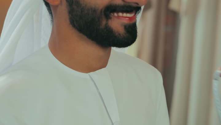 Men's tailoring and clothing shop, close-up of a young Emirati man wearing a navy blue kandura taking measurements of a customer's body using a tape measure, mastery of clothing making, concept of the world of fashion and style, practicing the tailoring profession, skill of mastering tailoring youth clothing, handicrafts and crafts.