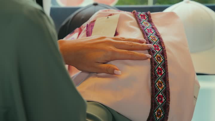 عرض الأزياء والموديلات الجديده ، مهنة الخياطه وتفصيل الثياب العصريه الحديثه, شراء عباءات عصرية حديثه في متجر من السوق في الامارات العربيه المتحده ، تصوير مقرب لامراة عربيه خليجيه اماراتية ترتدي العباءه تقوم بشراء عباءه جديده .