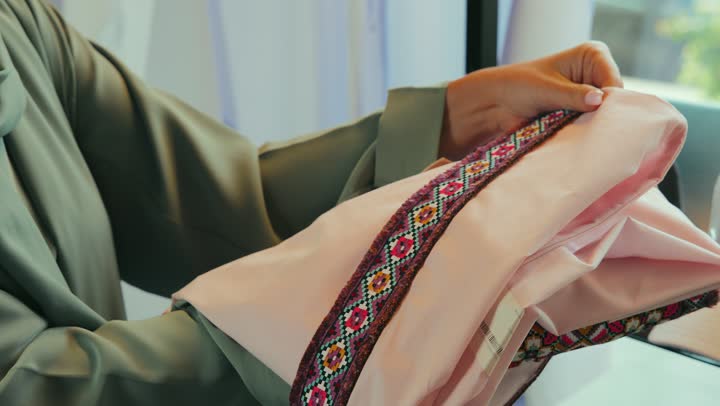 The profession of tailoring and tailoring modern clothes, buying modern abayas in a store in the market in the United Arab Emirates, a close-up of an Arab Gulf Emirati woman wearing an abaya, adorning herself and shopping, a Saudi woman buying abayas, fashion show and new models